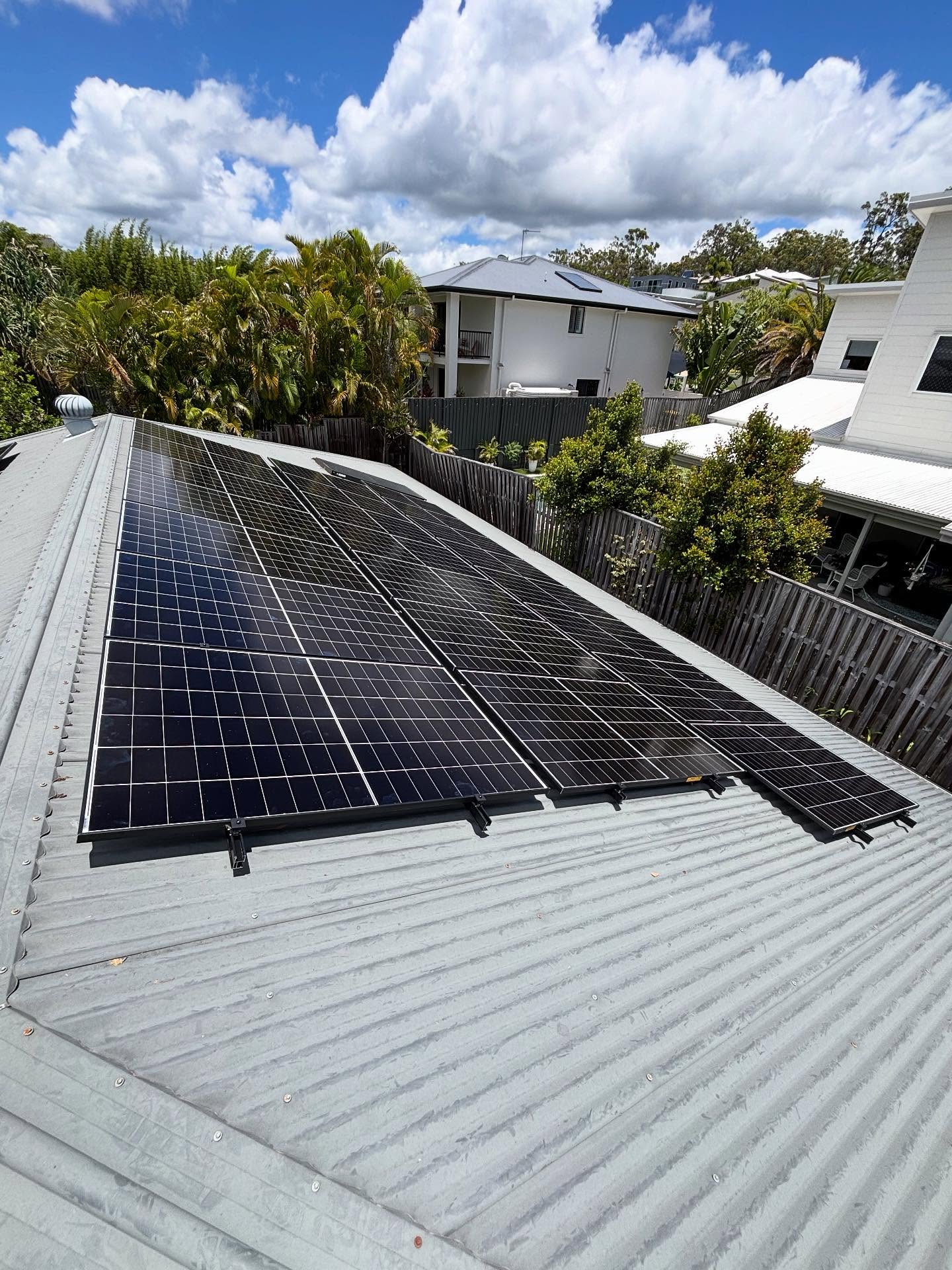 Solar panels on corrugated iron roof with palm trees